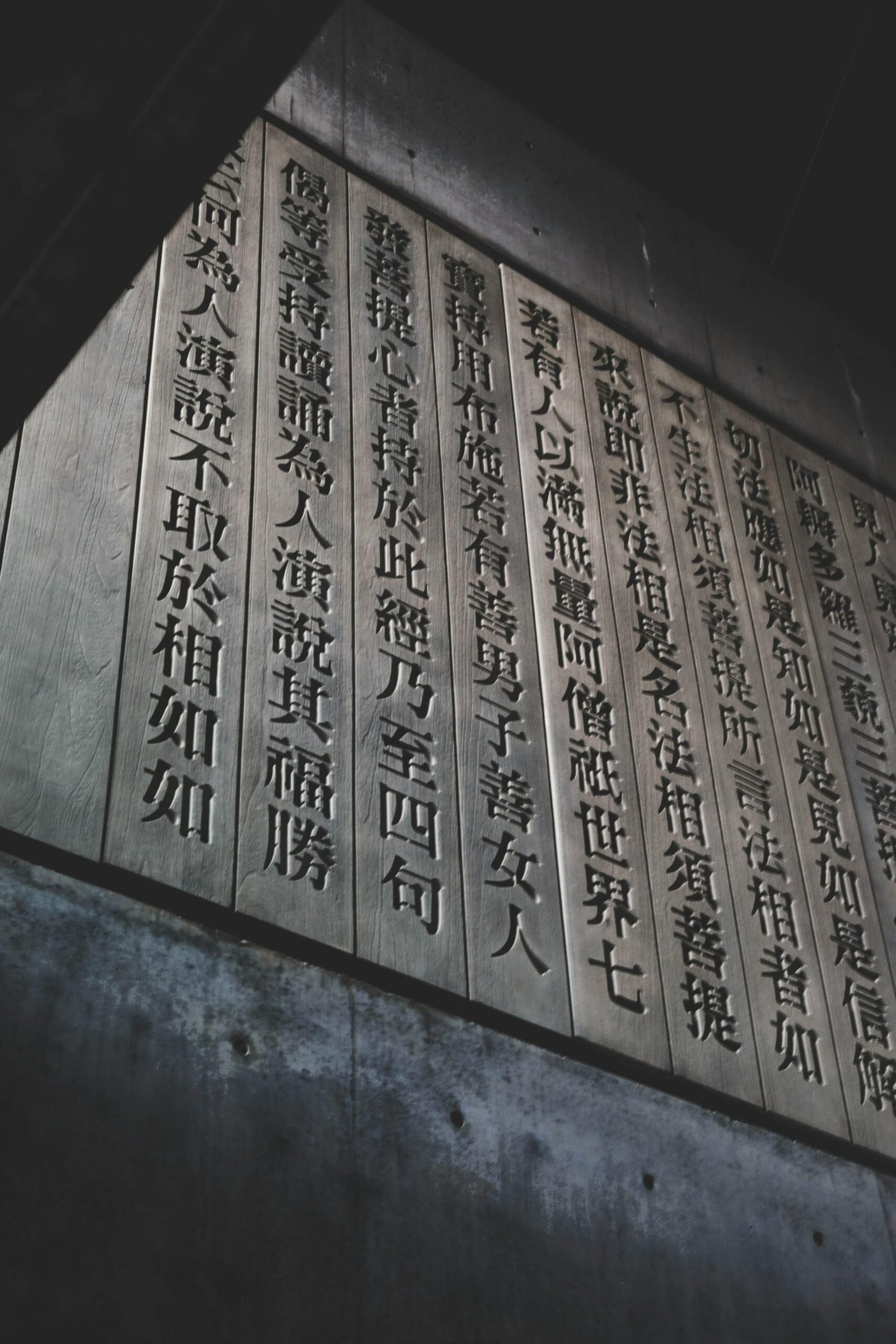 Low angle shot of traditional Chinese calligraphy on a historic wooden panel indoors.